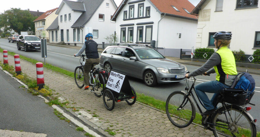 Radfahrerin mit Transparent auf schmalem Radweg